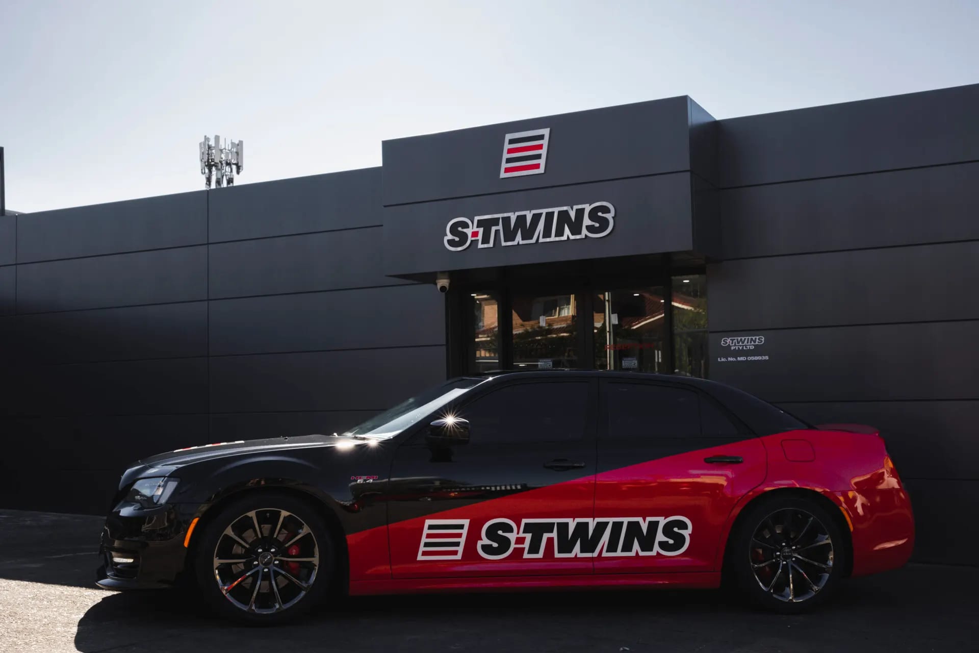 S-Twins hero banner showing a branded performance car in front of the workshop